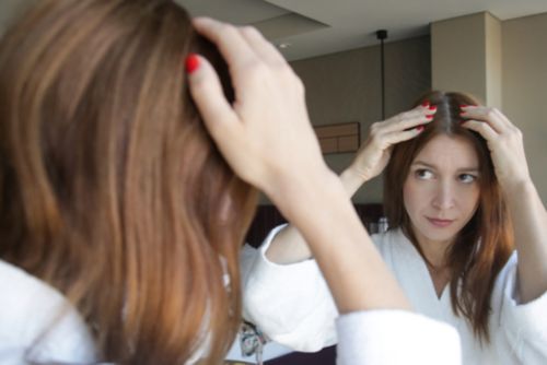 Woman checks scalp in mirror