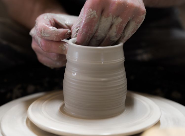 Close up of hands creating a clay vase on a pottery wheel