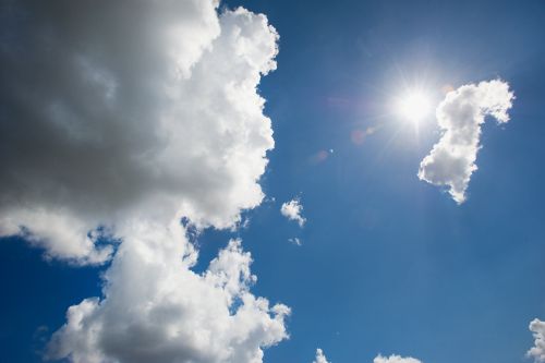 Cette photo montre un ciel bleu avec quelques nuages blancs et un soleil éclatant.