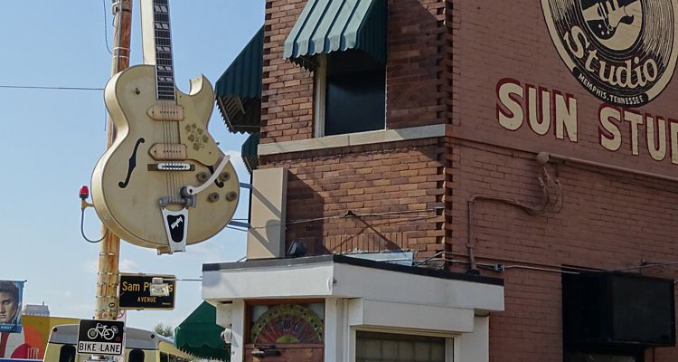 Exterior of Sun Studios recording studio featuring a sculpture of a yellow guitar and artwork of records with the Sun Studios logo in Memphis.