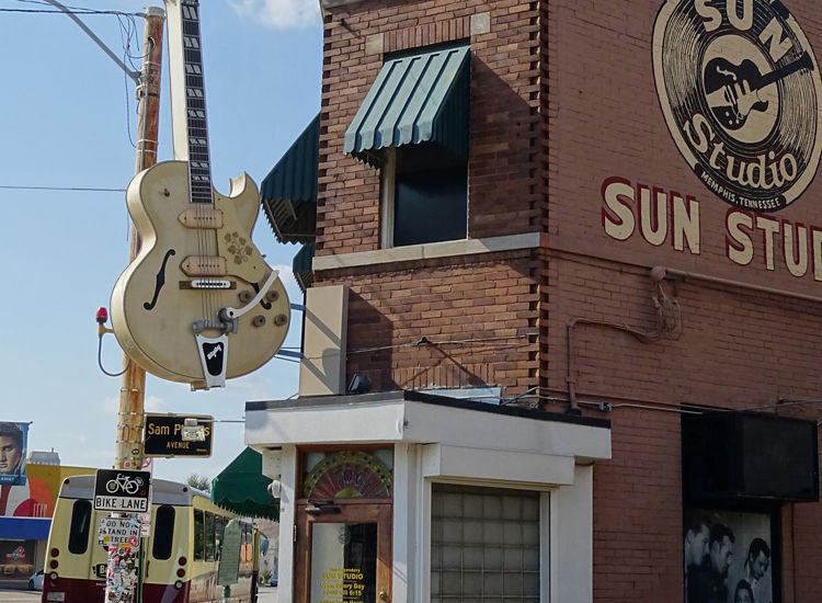 Exterior of Sun Studios recording studio featuring a sculpture of a yellow guitar and artwork of records with the Sun Studios logo in Memphis.