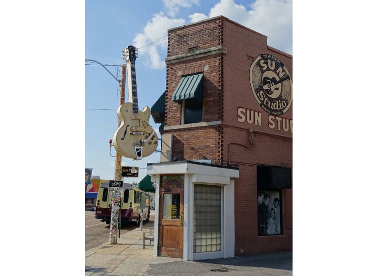 Exterior of Sun Studios recording studio featuring a sculpture of a yellow guitar and artwork of records with the Sun Studios logo in Memphis.