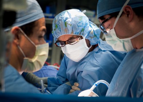 Три члена хирургической бригады проводят операцию в операционной.