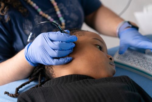 Technician performs transcranial doppler ultrasound on child