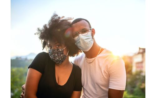 Young black couple wearing face masks outside. 