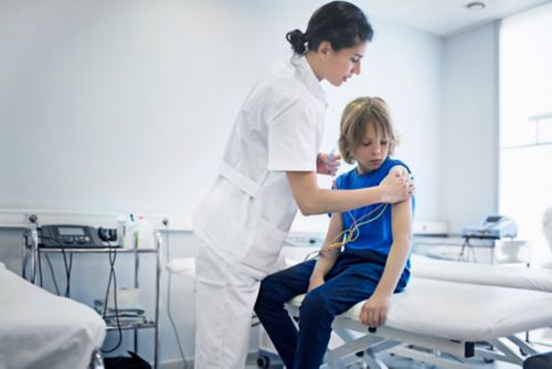 Nurse attaches TENS unit pads to little boy's skin.