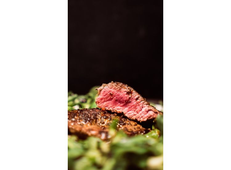   Dish of hanger steak on greens