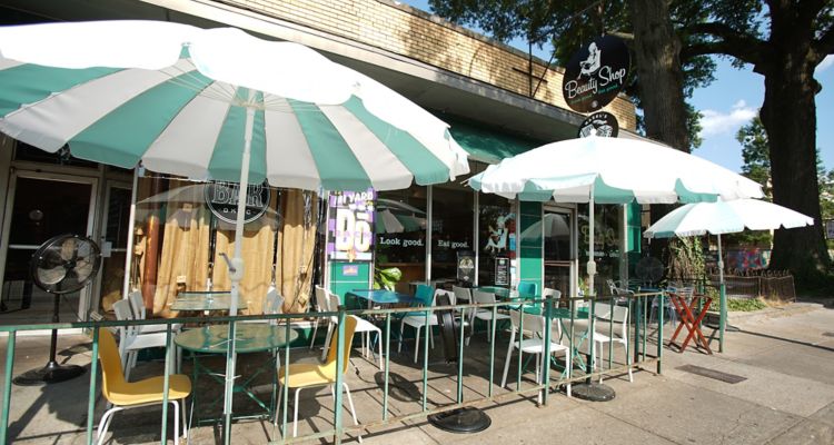 Front entrance of Beauty Shop Restaurant in Memphis with green and white cafe tables outside.