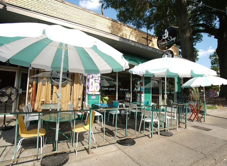 Front entrance of Beauty Shop Restaurant in Memphis with green and white cafe tables outside.