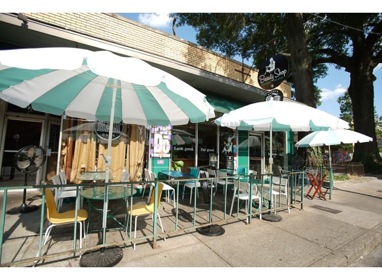 Front entrance of Beauty Shop Restaurant in Memphis with green and white cafe tables outside.