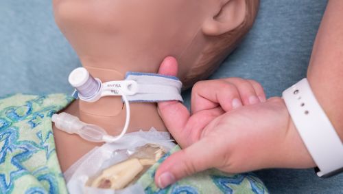 A nurse demonstrates secure trach ties on a mannequin