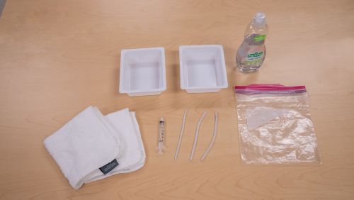 Suministros para la limpieza de un tubo de traqueotomía, incluidos jabón, toalla limpia, recipientes de plástico y una bolsa de plástico con precinto