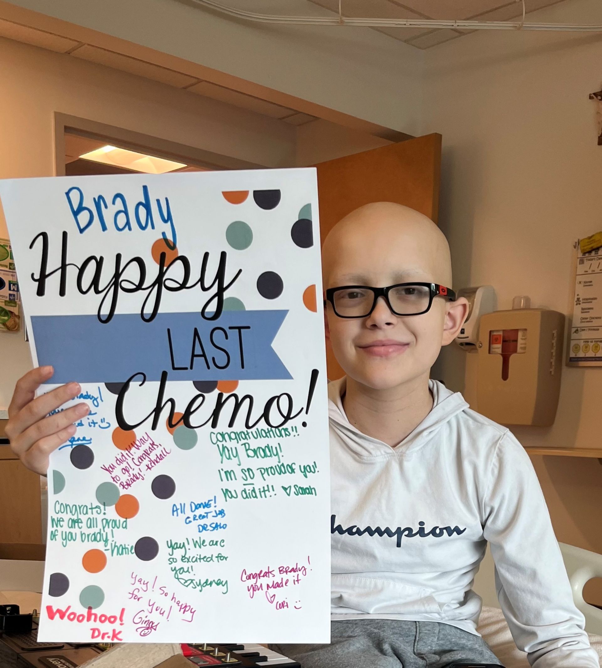 Child cancer patient holds up handmade poster that saysBrady happy last chemo