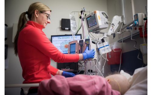 St. Jude nurse looks at vitals on monitor in pediatric cancer patient's room.