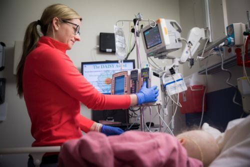 Ilustracja przedstawiająca członka personelu pielęgniarskiego, który dostosowuje ustawienia monitora podłączonego do pacjenta z nowotworem wieku dziecięcego.