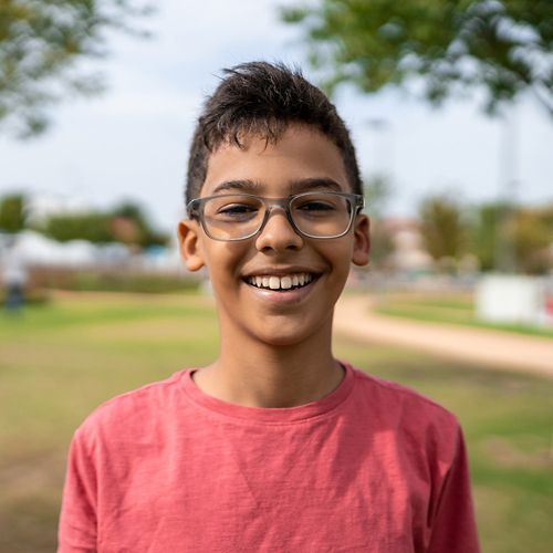 Smiling young boy wearing glasses in a city park