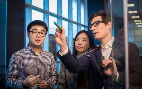 Research faculty member and students looking at computer screen