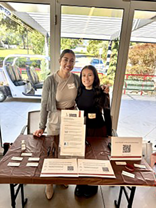 Two women standing behind an information table