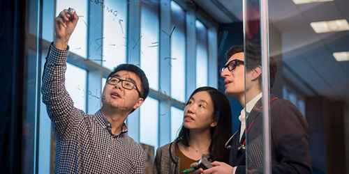 3 scientists working on glass board