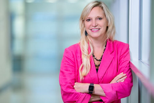 Researcher wearing bright pink jacket smiles at camera.