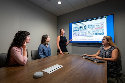 people in a meeting with a computer screen on wall