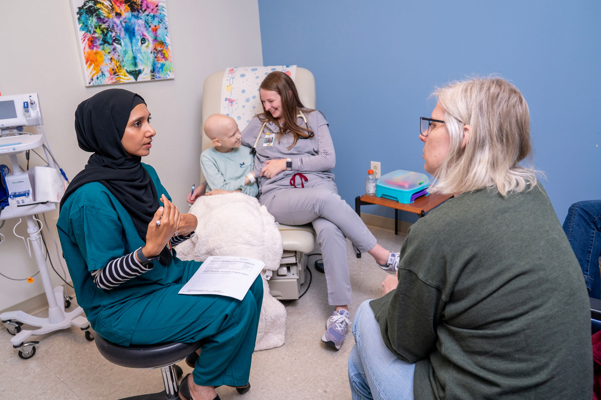 A doctor speaking with patient's mother, with patient and nurse in background