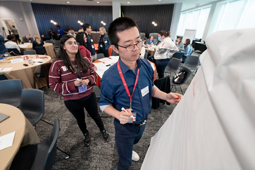 man writing on flip chart as woman watches