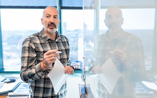 Image of man in flannel shirt reflected in whiteboard
