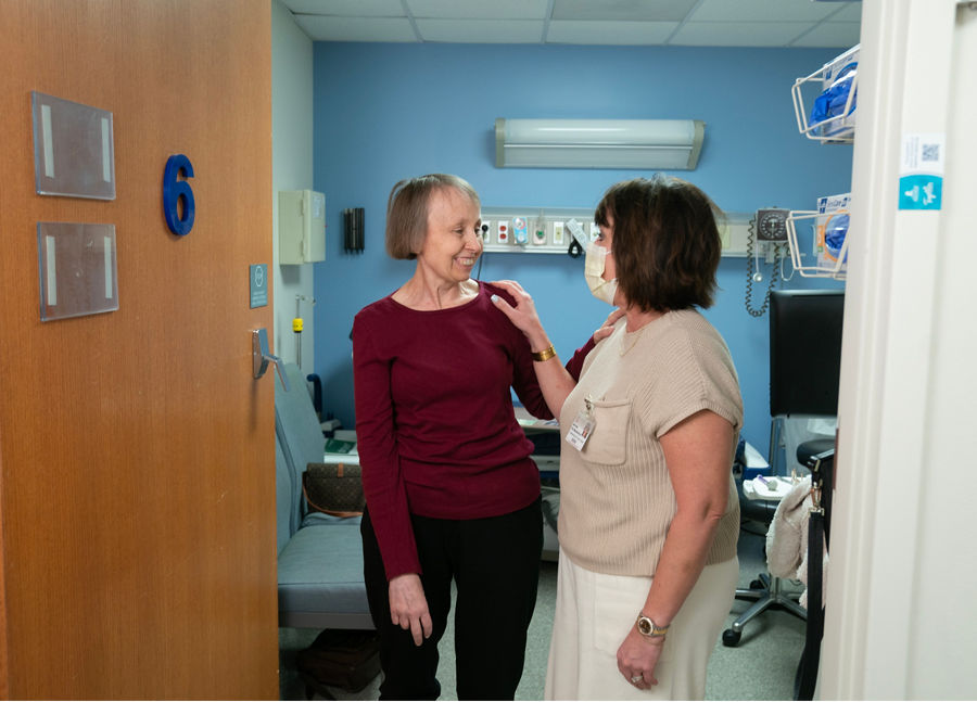 Dos mujeres que conversan de pie en la puerta de una habitación de hospital 
