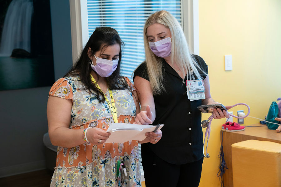 two masked healthcare workers looking at a sheet of paper