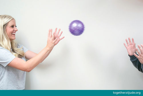 Dos personas jugando a lanzarse una pelota morada pequeña