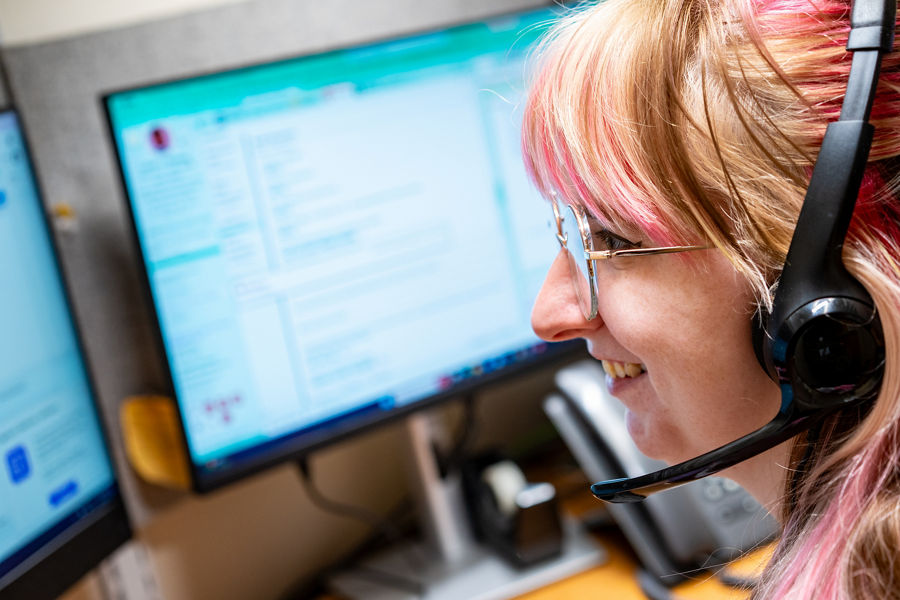 Woman wearing a headset in front of computer monitors