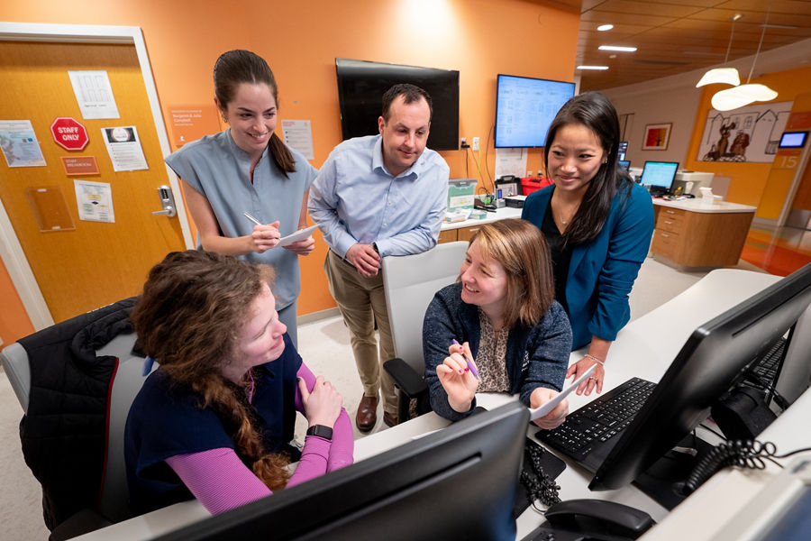 Group of people sitting around of a computer.
