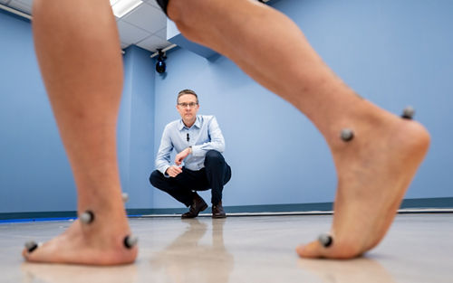 man observing a patient walking with sensors on their feet