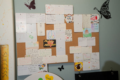 Vision board with butterflies and various papers attached to it