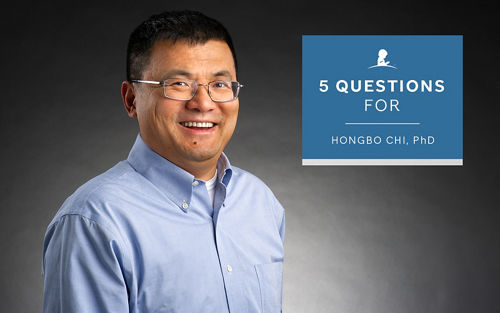 A headshot of a smiling man in a blue shirt