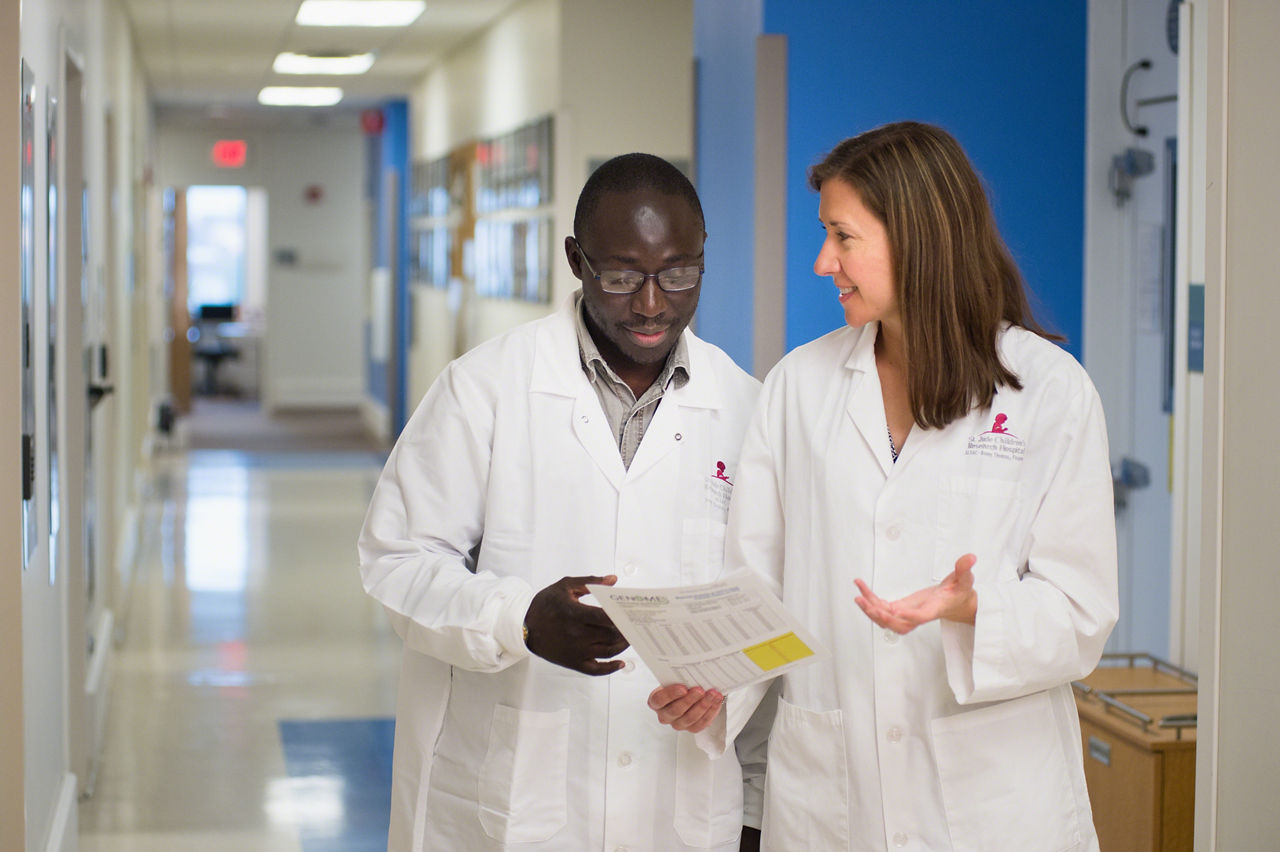 Two people in white coats talking about something on a  piece of paper