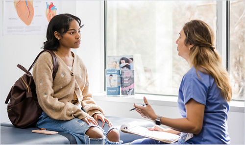 A young patient holding a backpack talking with a healthcare professional.