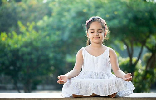 Niña meditando al aire libre en el parque
