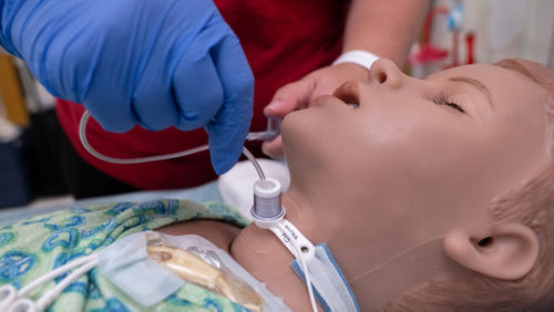 Una enfermera practica el uso de tubos de traqueotomía en un maniquí de niño