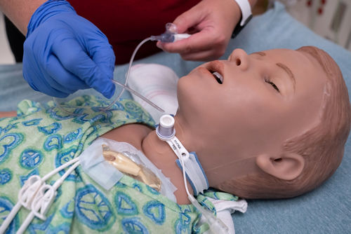 Una enfermera practica el uso de tubos de traqueotomía en un maniquí de niño