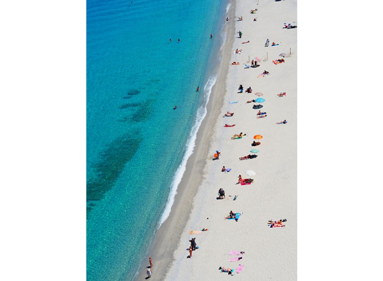 Aerial view of white sandy beach and aqua blue ocean with beach goers