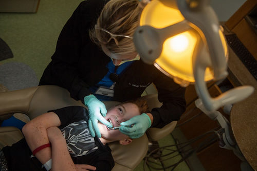 Higienista dental que revisa los dientes de un niño