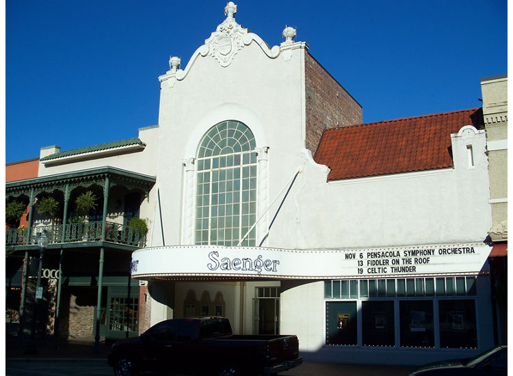 Exterior of Pensacola Saenger Theater, marquis with show dates, white building with red accents