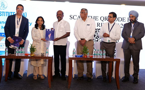 Group of people on a stage. Two are holding an award