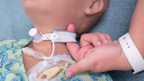 Un integrante del personal de enfermería demuestra cómo se ajustan los sujetadores del tubo de traqueotomía en un maniquí
