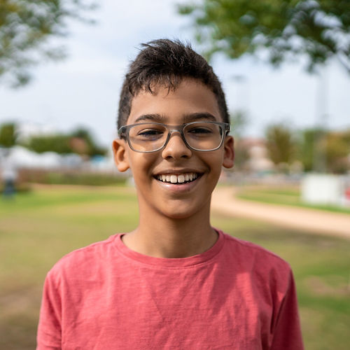 Smiling young boy wearing glasses in a city park
