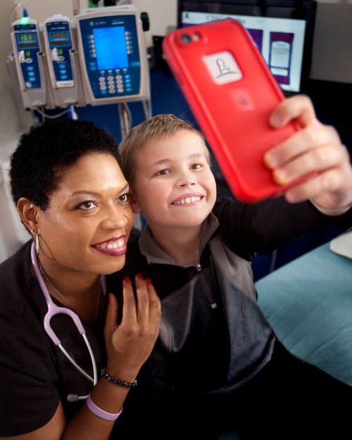 nurse and young pediatric cancer patient taking a selfie together