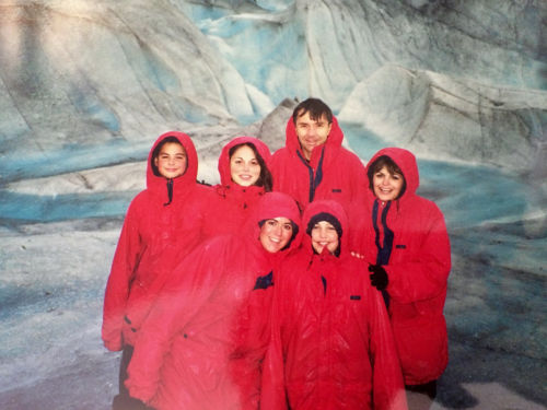 Family standign in front of wall of ice all wearing matching red jackets.