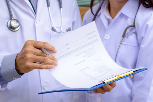 Two care team members holding a pathology report